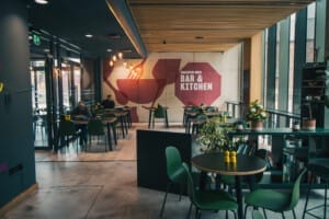 An interior shot of a modern cafe with dark furniture and a large mural on the wall.